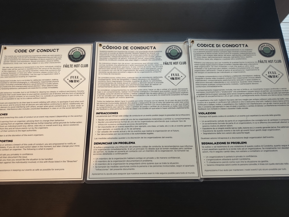 A spread of the printed and laminated copies of the code of conduct, ordered as English, Spanish, then Italian